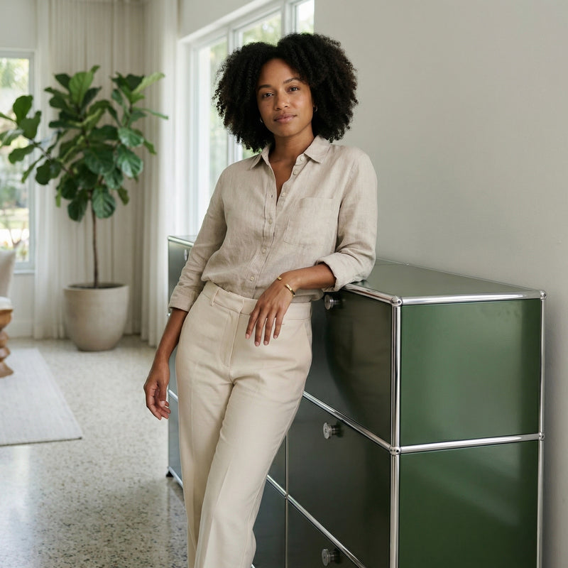 Lifestyle image of a woman leaning on an olive green USM Haller storage unit in a bright modern interior